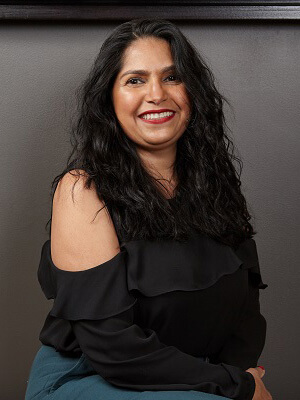 smiling woman with long black hair wearing red lipstick and black blouse