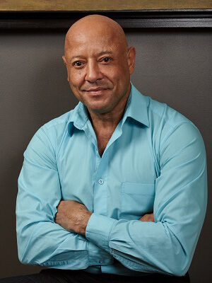 smiling man wearing light blue button up and crossing his arms