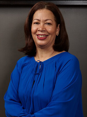 smiling brunette woman wearing red lipstick and blue blouse